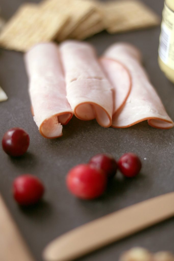 Rolls of ham on an autumn cheese board.