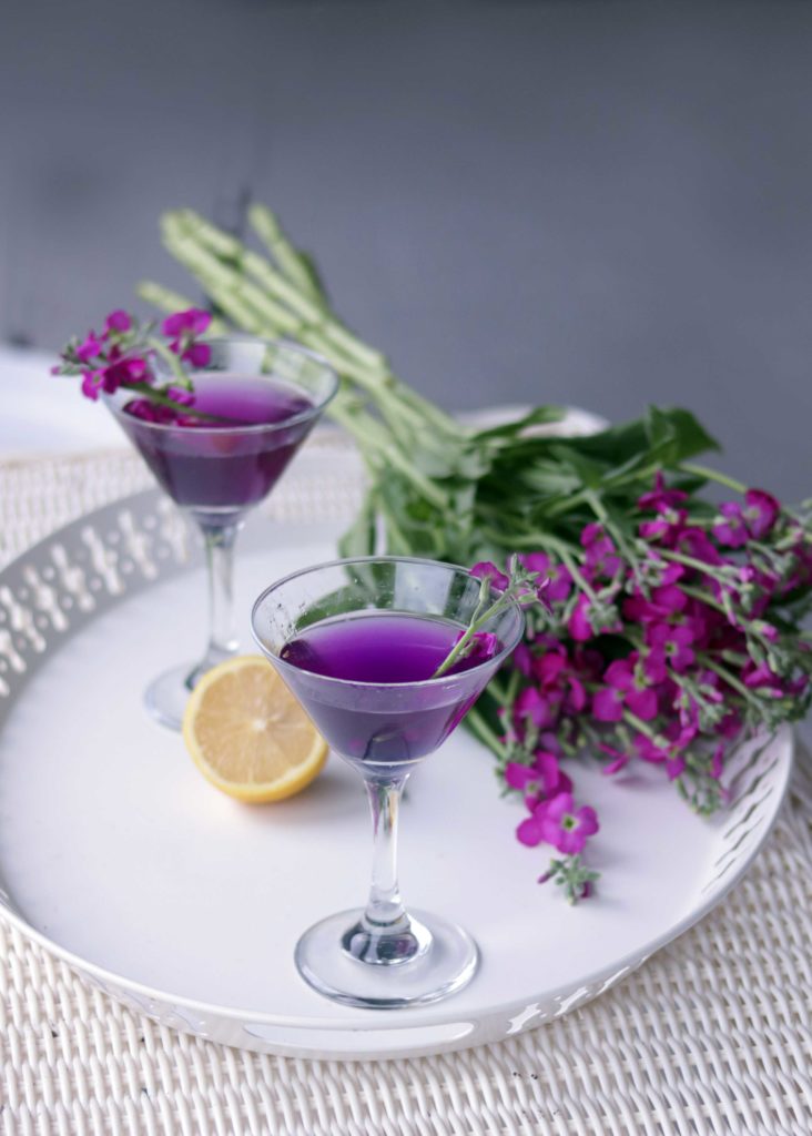 Purple martini with flower garnish.